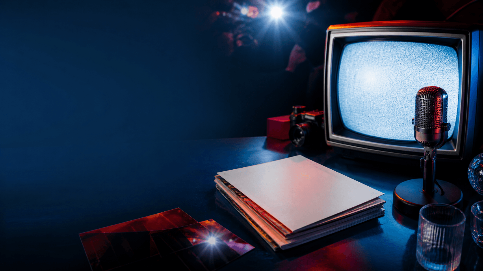Mesa editorial com televisão, microfone e revistas sem texto